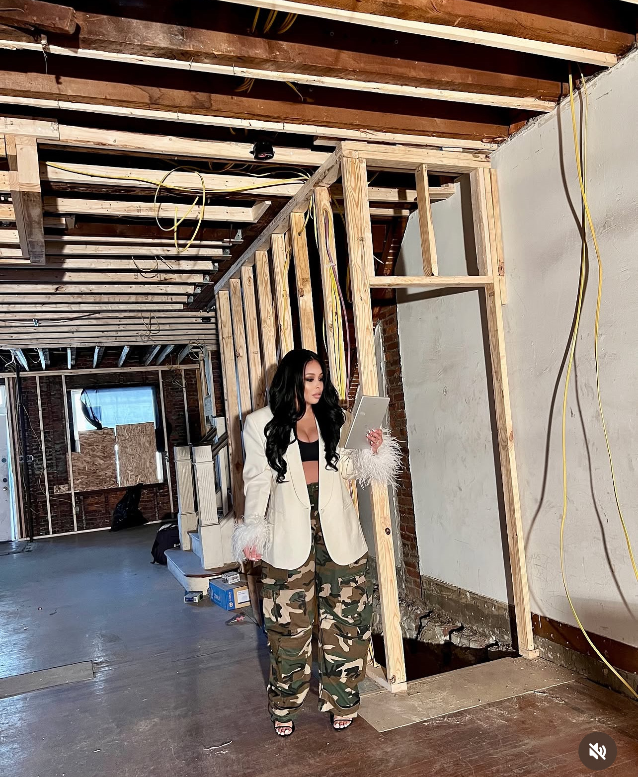 Zena Dixon reviewing a tablet inside a renovation project with exposed framing